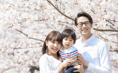 桜の木の前で記念撮影する家族